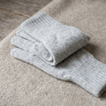 Close-up of light grey cashmere gloves highlighting fine fibers and subtle texture.