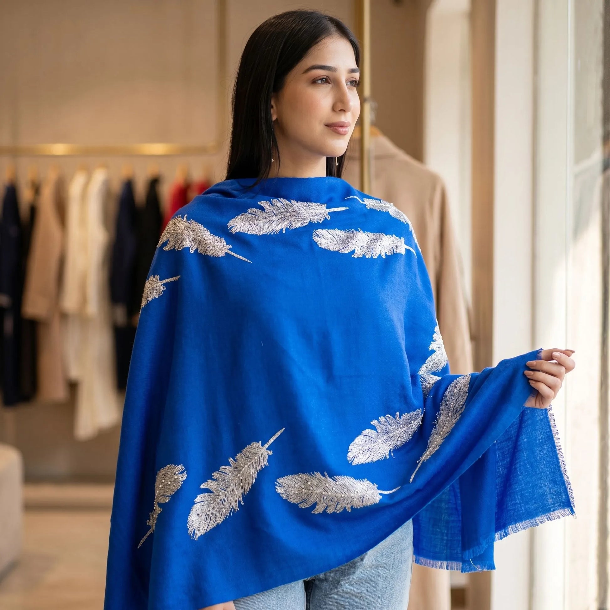 Close-up of a luxurious pashmina stole with feather and bead embellishments draped over a model's shoulders, highlighting texture and detail.