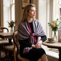 Elegant female model wearing a reversible pashmina cashmere silk scarf with embroidery in a luxury London cafe scene.