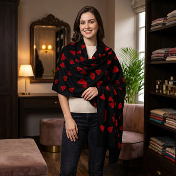 Full-body shot of woman in cozy indoor setting wearing large velvet hearts pashmina stole styled around her neck and shoulders.